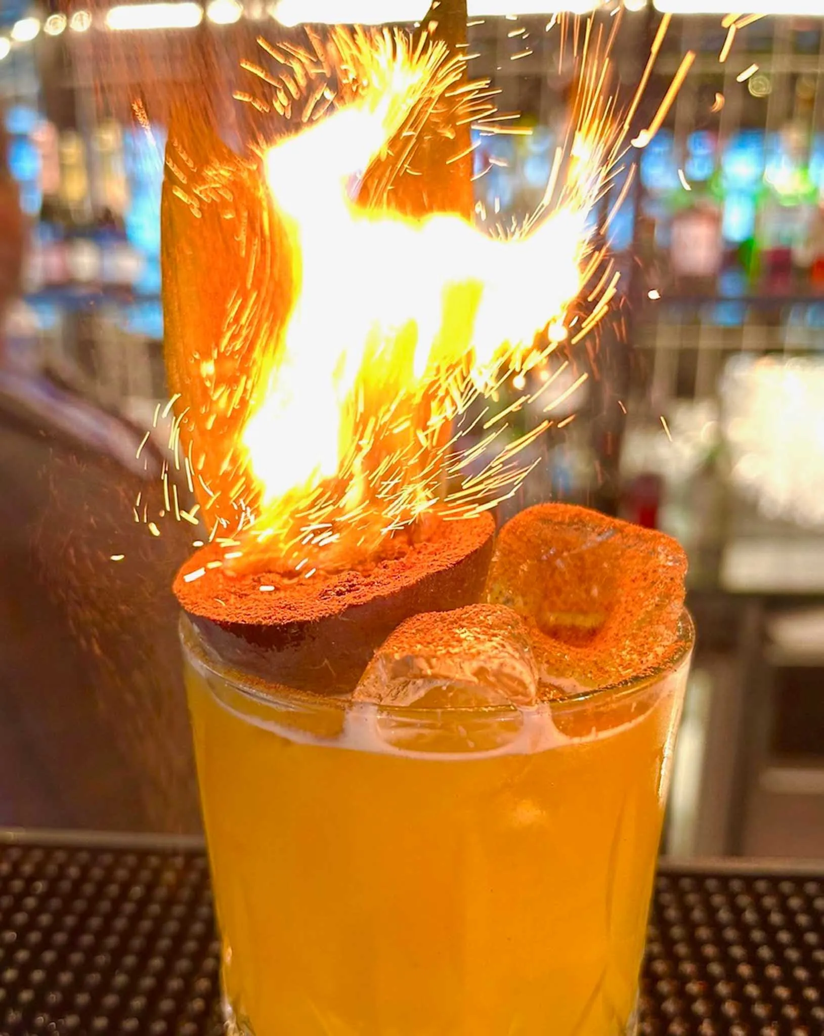 A glass of orange juice with a flame in it.