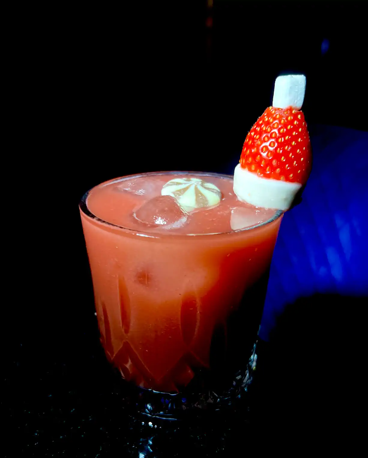A glass of red drink with a strawberry on top.